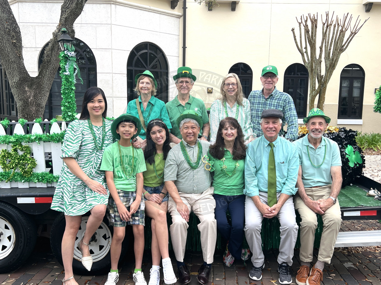 Mayor and city commission and their families sitting on the city's St. patrick's day float smiling.