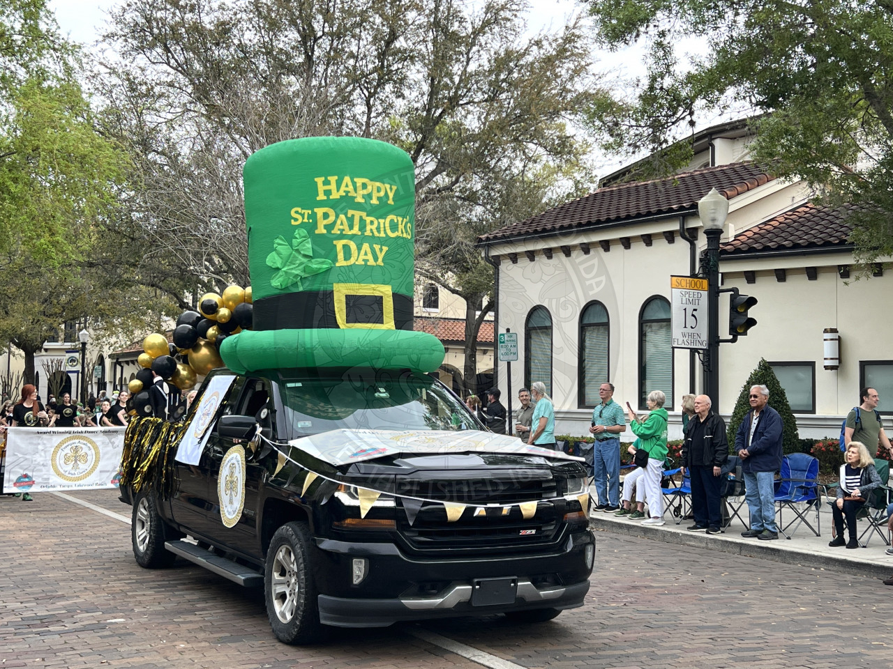 a black truck with a big inflatable on the top of roof that is a green top hat that says Happy St. Patrick's Day
