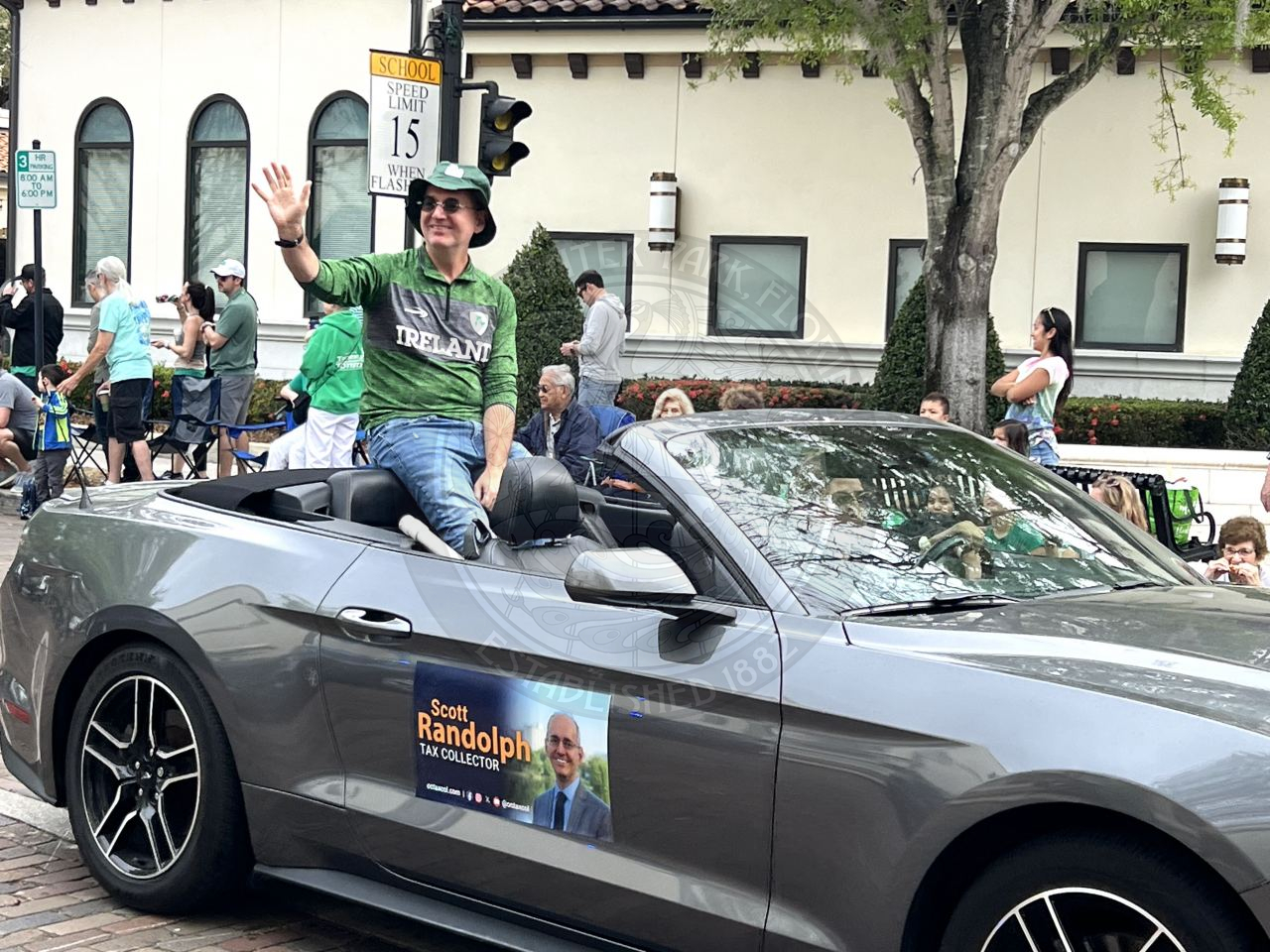 a politician sitting in the abck of a convertible smiling and waiving