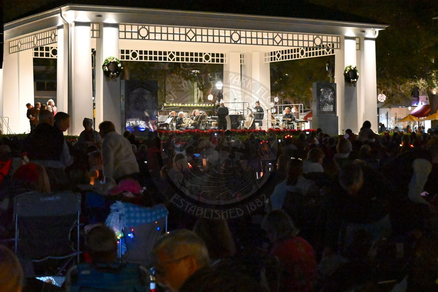 A crowd of people sitting down down watching a band perform a concert.