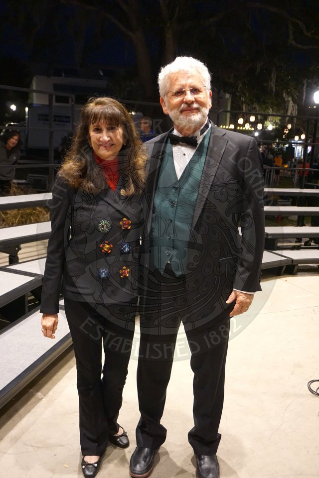 a man and a woman standing next to each other on the stage smiling.r