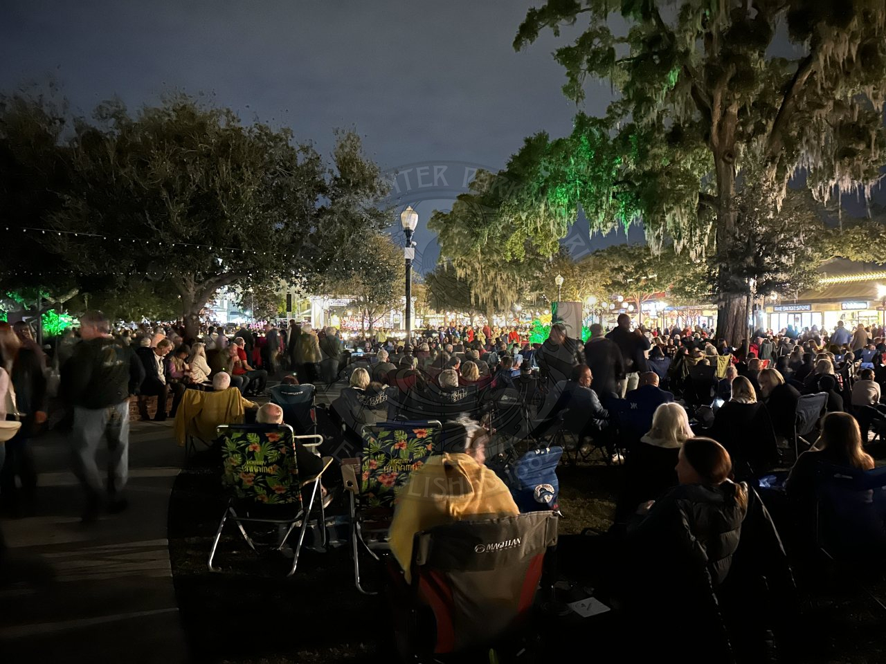 A crowd of people sitting down down watching a band perform a concert.