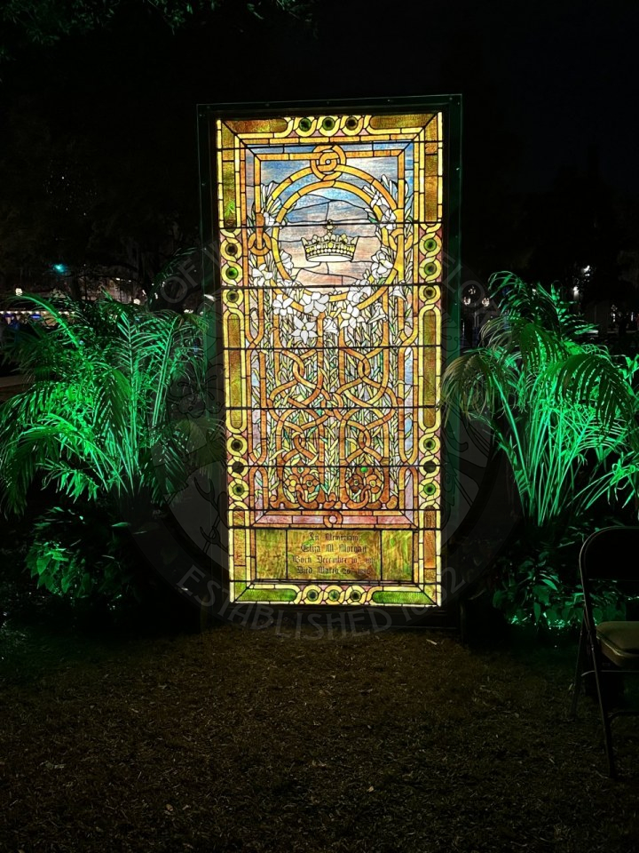 a tiffany stained glass window with two palm trees next to the painting.