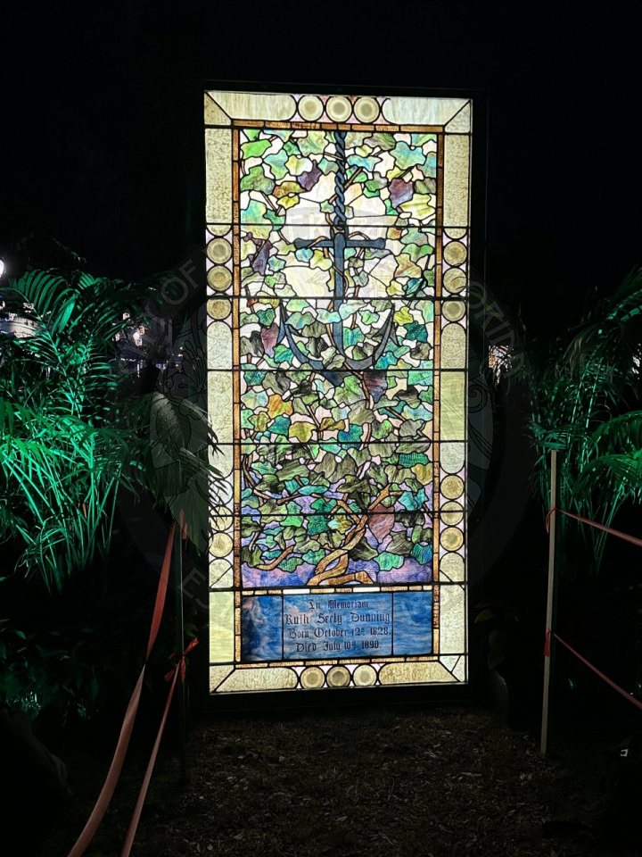 a tiffany stained glass window with two palm trees next to the painting.