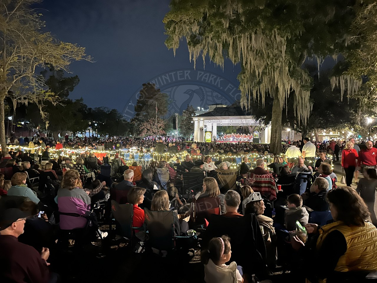 A crowd of people sitting down down watching a band perform a concert.
