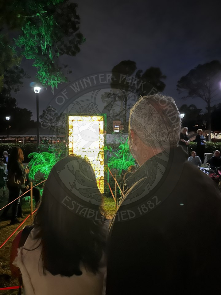the backside of a man and woman looking at a tiffany stained glass peice of art.