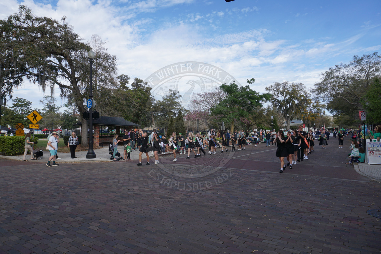 Group of kids walking in a line down a brick street
