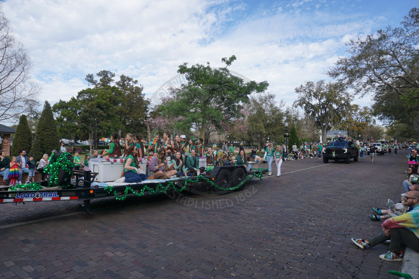 girl scout troop sitting on a trailer riding down brick road.