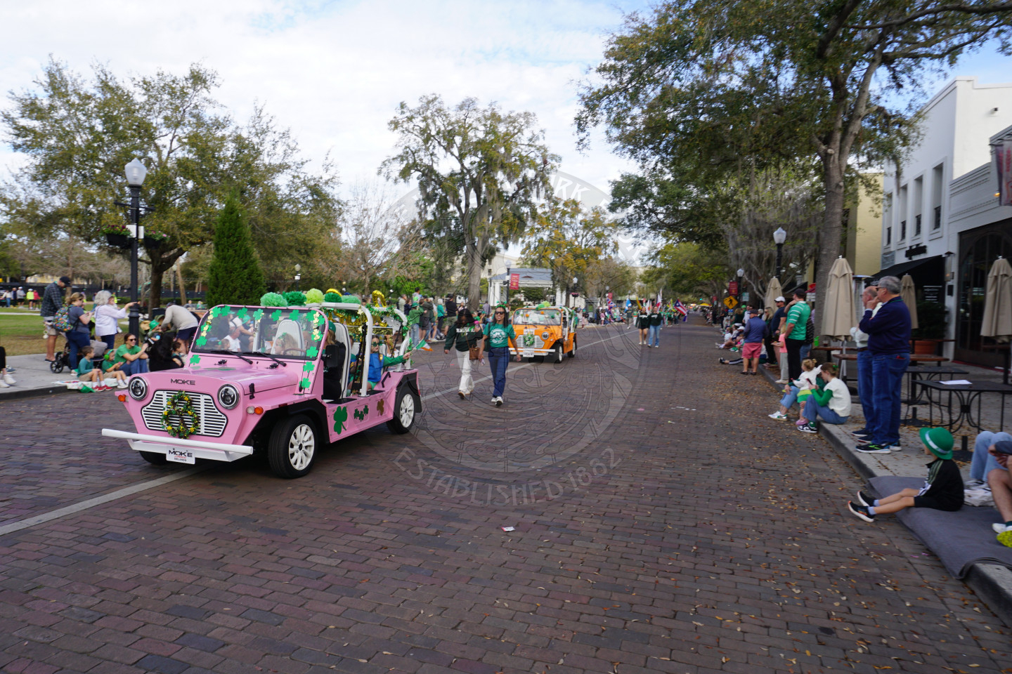 moke cars driving down a brick street.