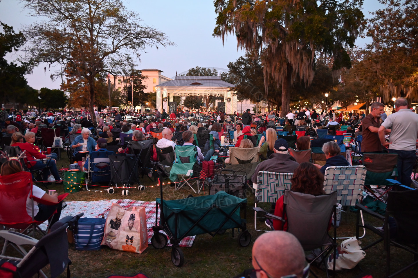 a view of a stage with a bunch of people sitting in lawn chiars.