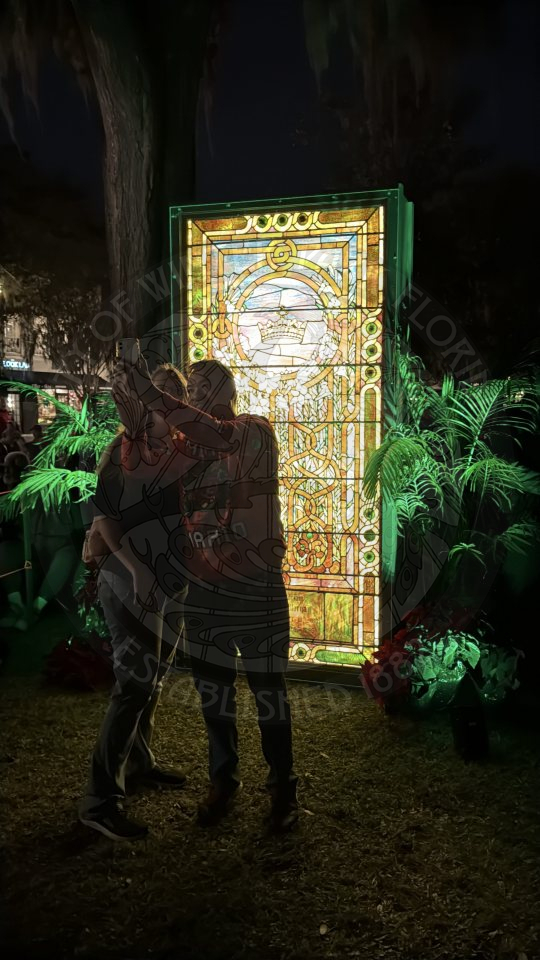 two people standing next to each other holding a phone taking a selfie in front of a tiffany mirror.