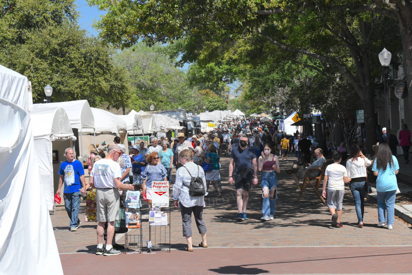 People walking on Park Avenue visiting artist booths at Winter Park Sidewalk Art Festival v