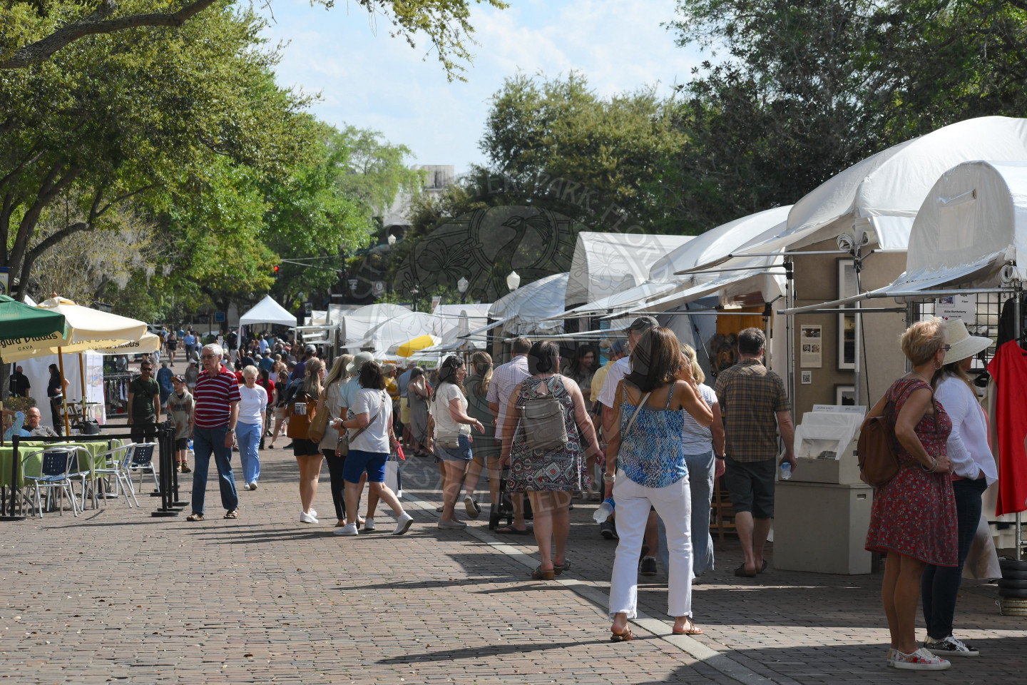 People walking on Park Avenue visiting artist booths at Winter Park Sidewalk Art Festival