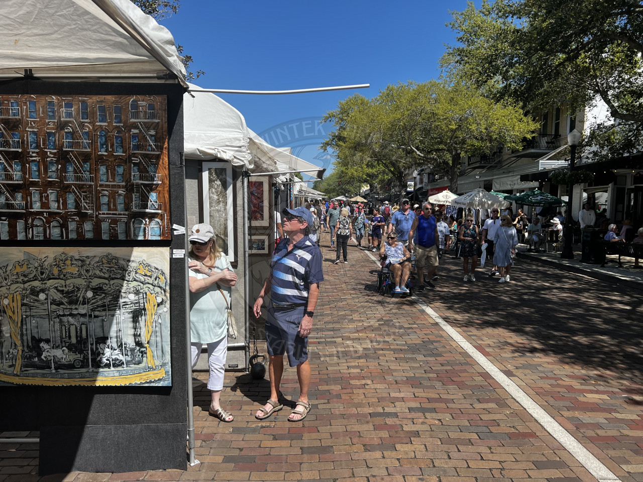 People walking on Park Avenue visiting artist booths at Winter Park Sidewalk Art Festival