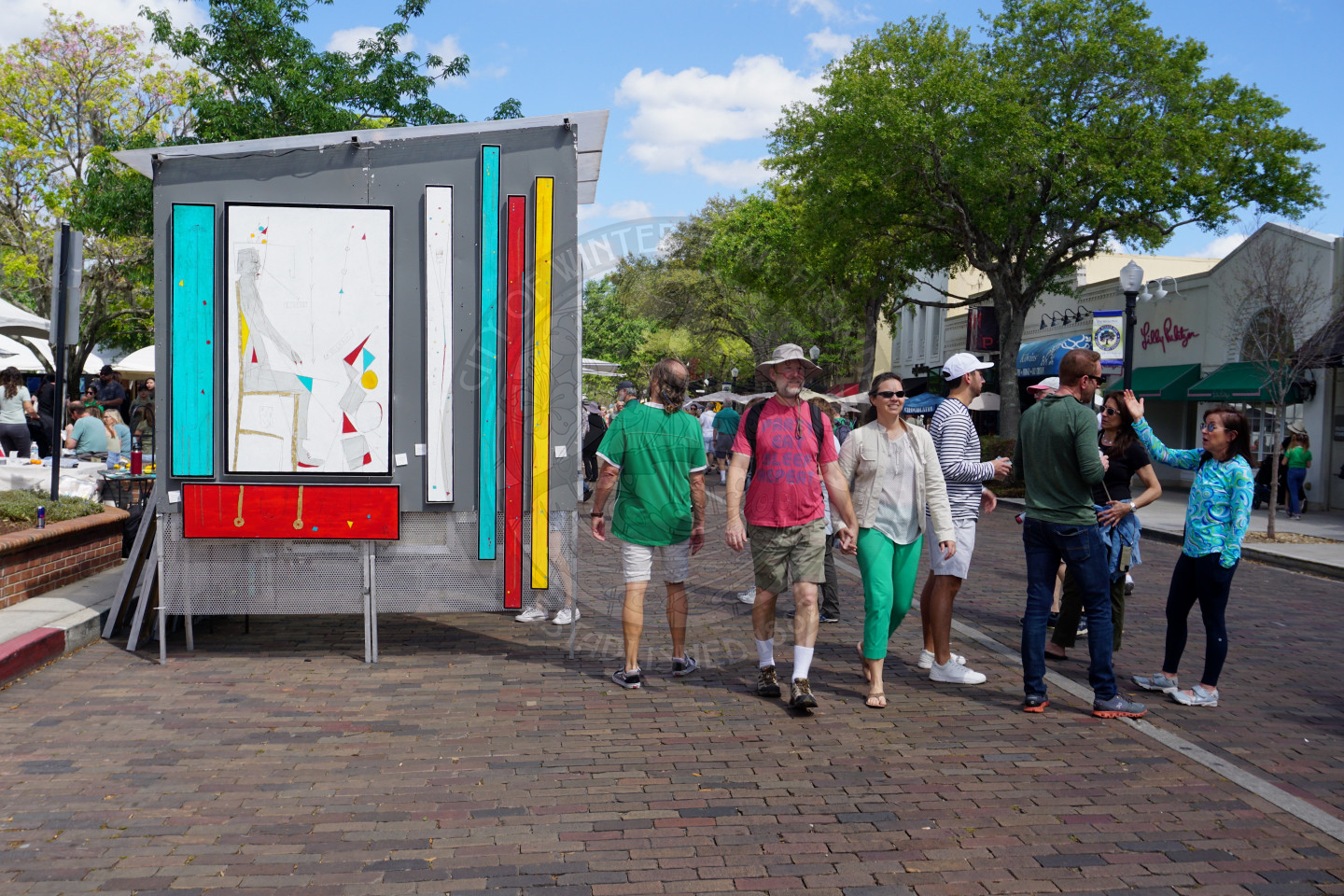 A booth with wall art on Park Avenue with people walking down the street.