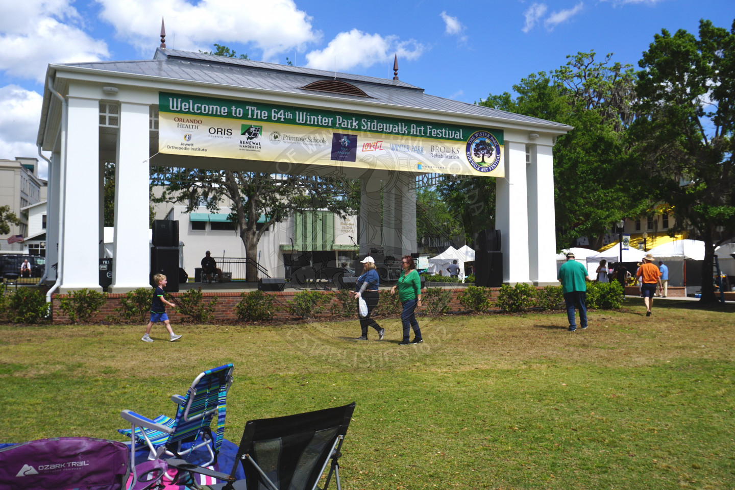 Central Park Main Stage with a banner that states "Welcome to the 64th Annual Winter Park Sidewalk Art Festival"