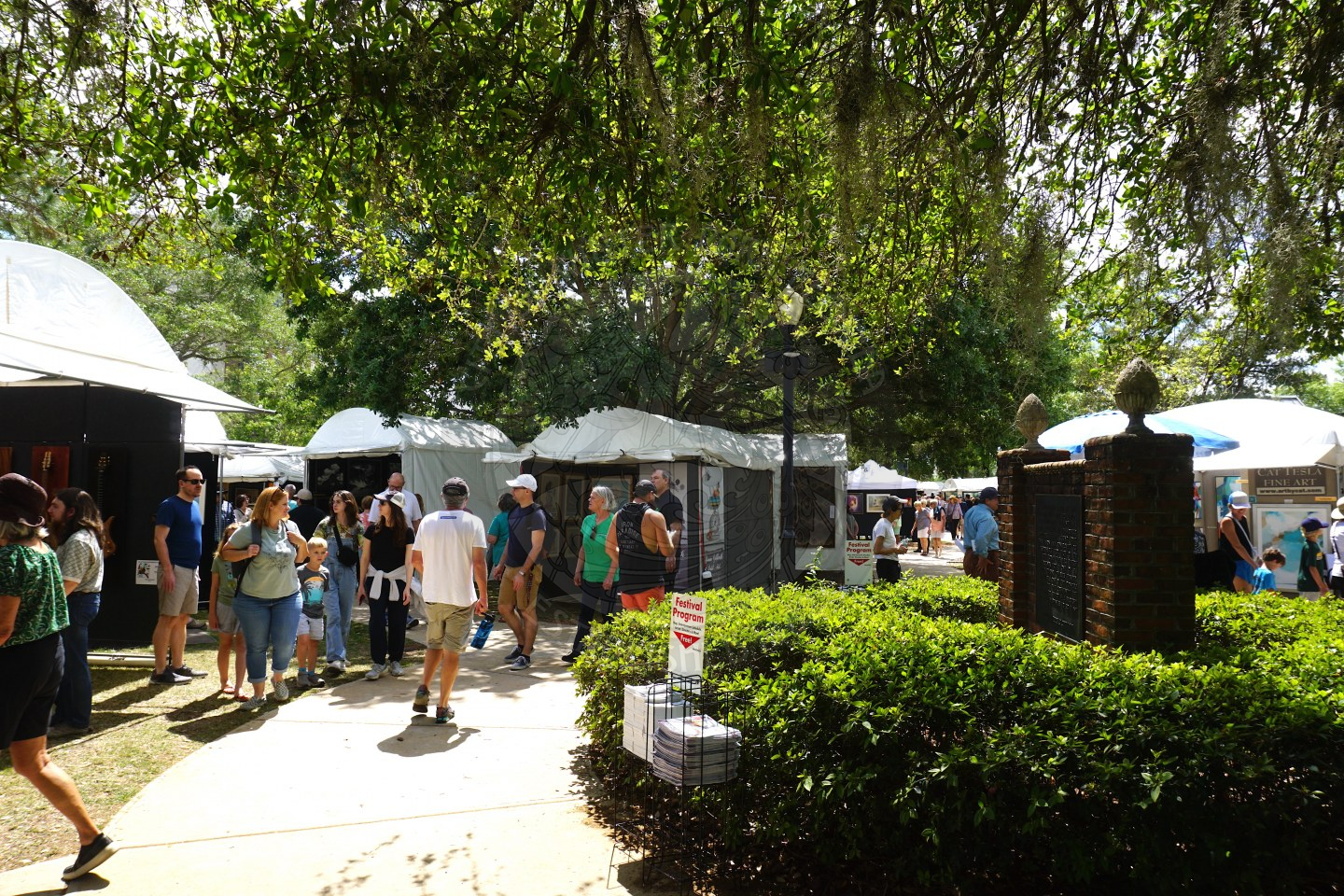 pathway of people waking through tents to view all kinds of art