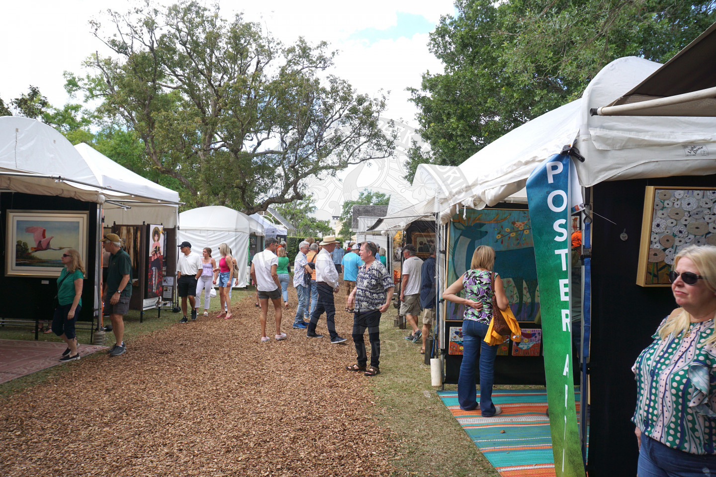 mulch pathway with tents lined up on both sides of the walkway filled with art