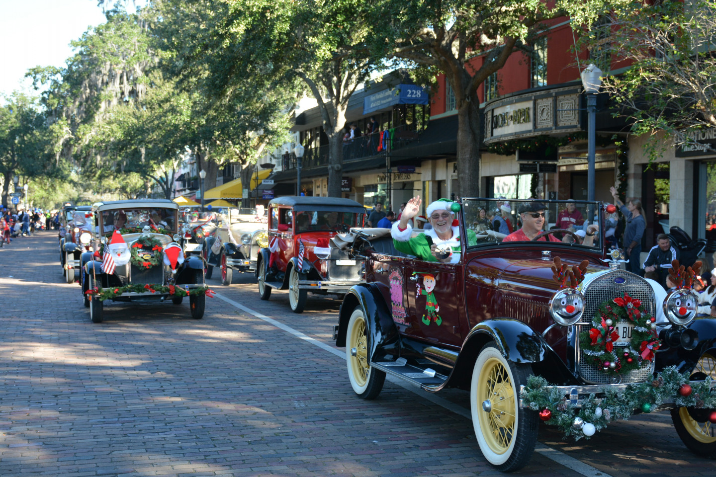 man waving from an old school car during the parade