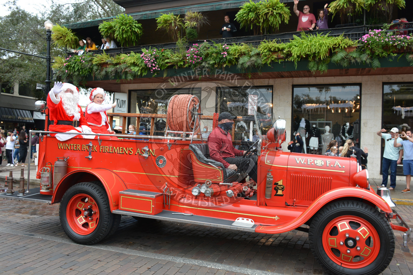Santa and Mrs. Claus on the back of an old fashioned fire engine
