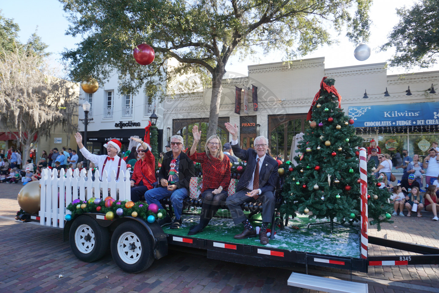 City Commission and family sitting down waving to people along Park Avenue.