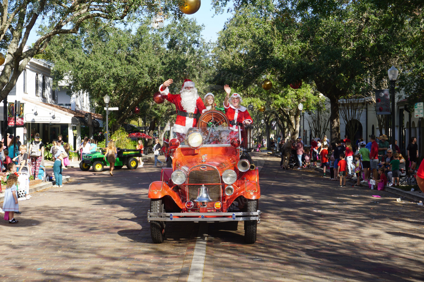 Mr. and Mrs. Claus in an old time car waving to the camera.