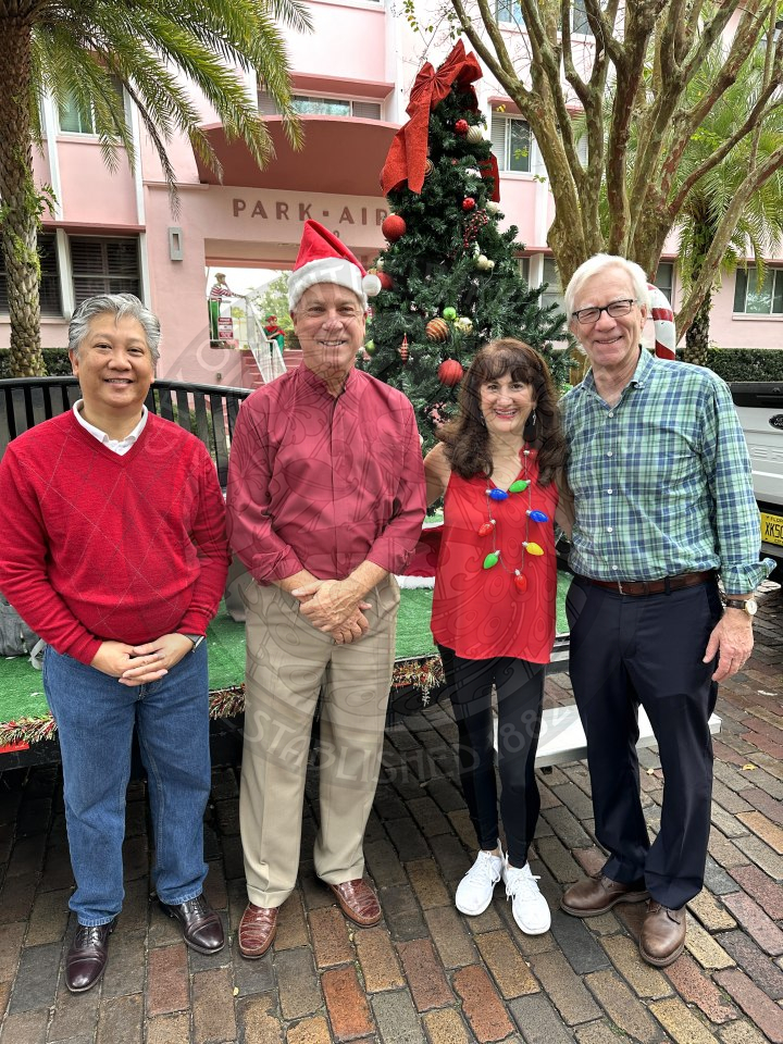 Mayor and Commission of Winter Park dressed in Christmas colorss tanding in front the parade float they will be sitting on for the Annual Christmas Parade.