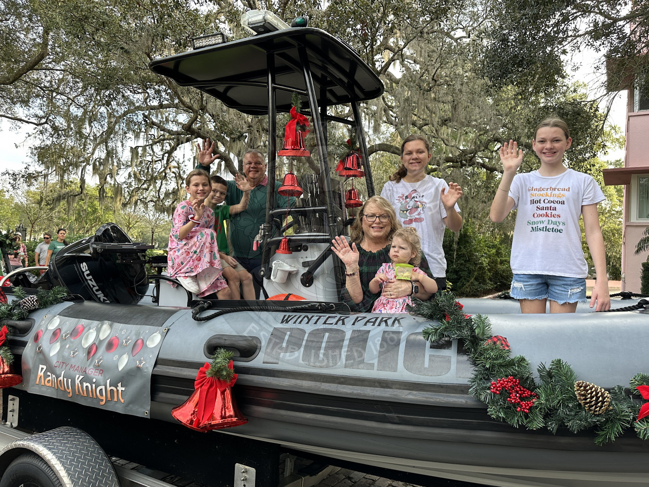 City Manager Randy Knight with his wife and grandkids riding on a boat waving for the Christmas parade.