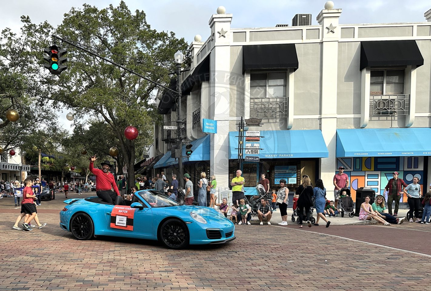 Orange County Mayor Jerry Demmings sitting on the back of a nice blue corvette waving to the crowd as he rides by on Park Avenue.
