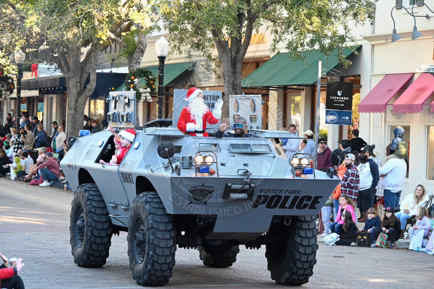Swat vehicle with a kid dressed up as santa in smiling.