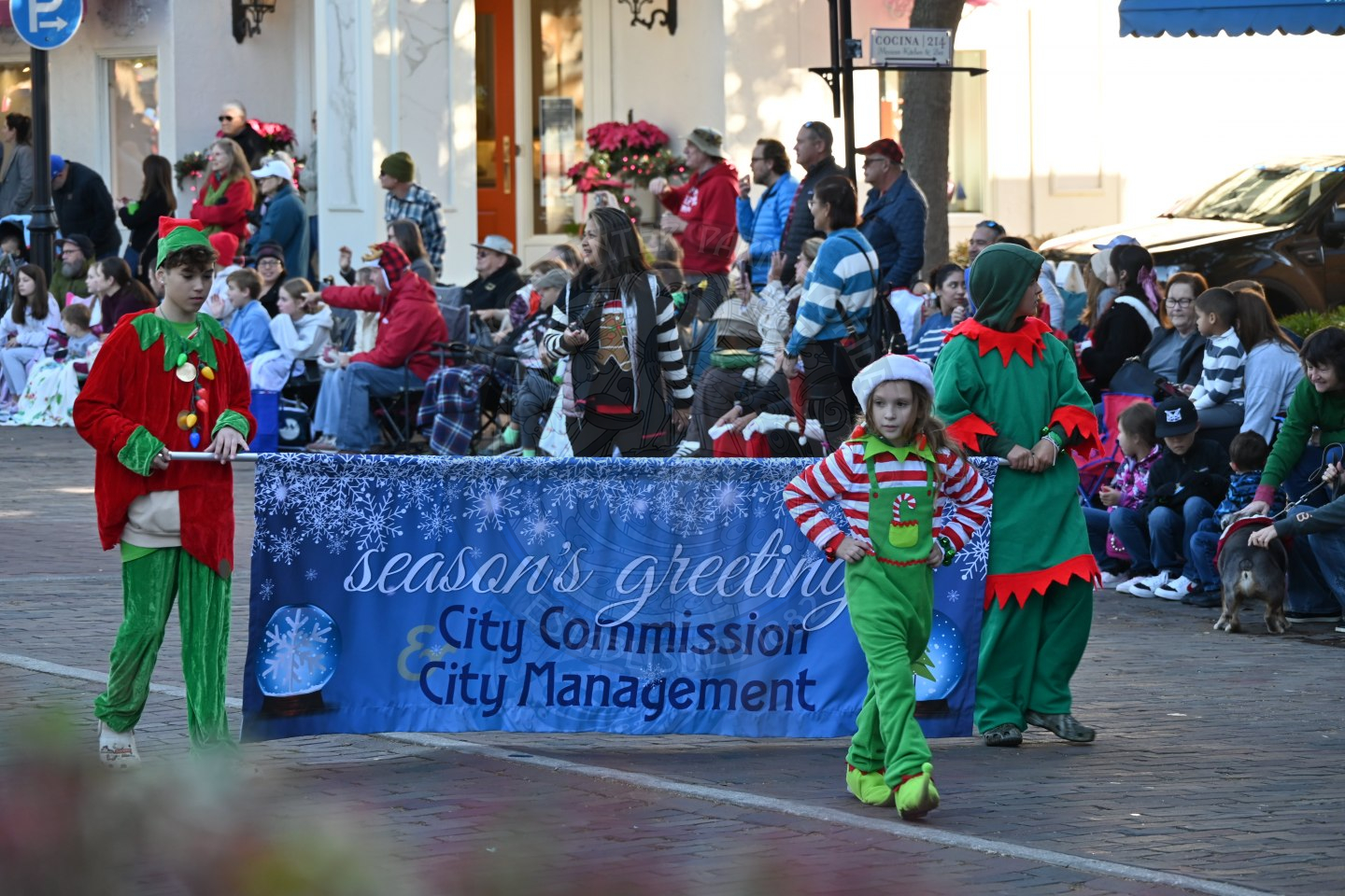 two kids dressed as elves holding a banner 