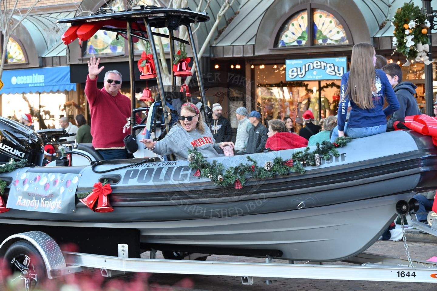 City Manager and his family sitting on a boat waving and smiling to everyone at the parade.