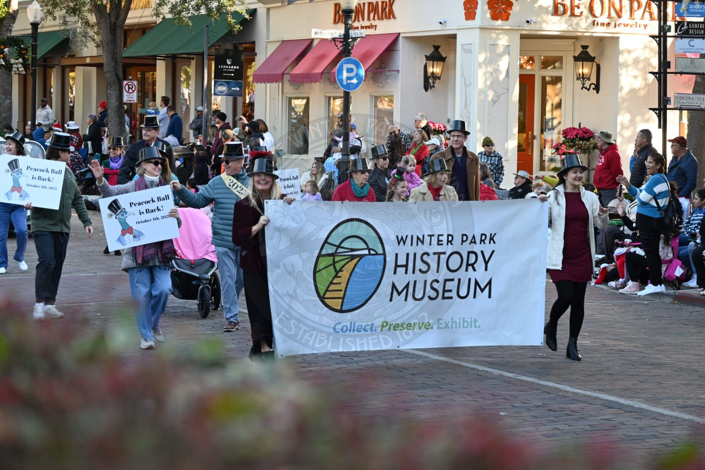 winter park history museum staff walking down park avenue holding a banner.