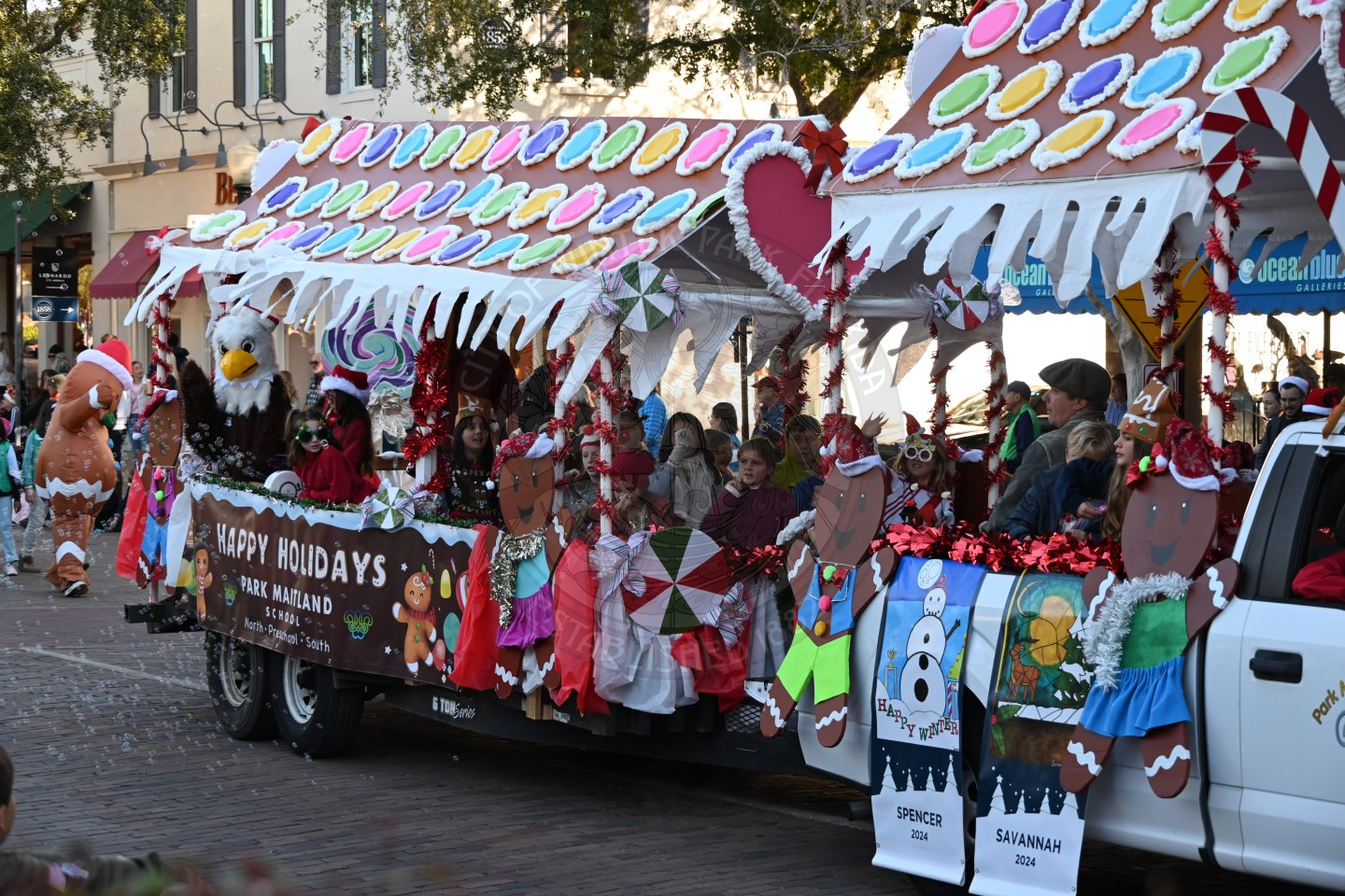 a trailer that is decorated as a gingerbread house with people sitting inside waving.