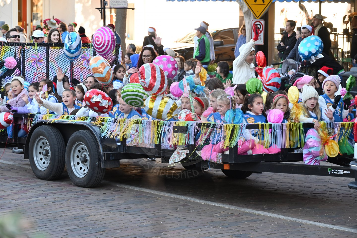 girl scouts sitting in the trailer bed waving and smiling.