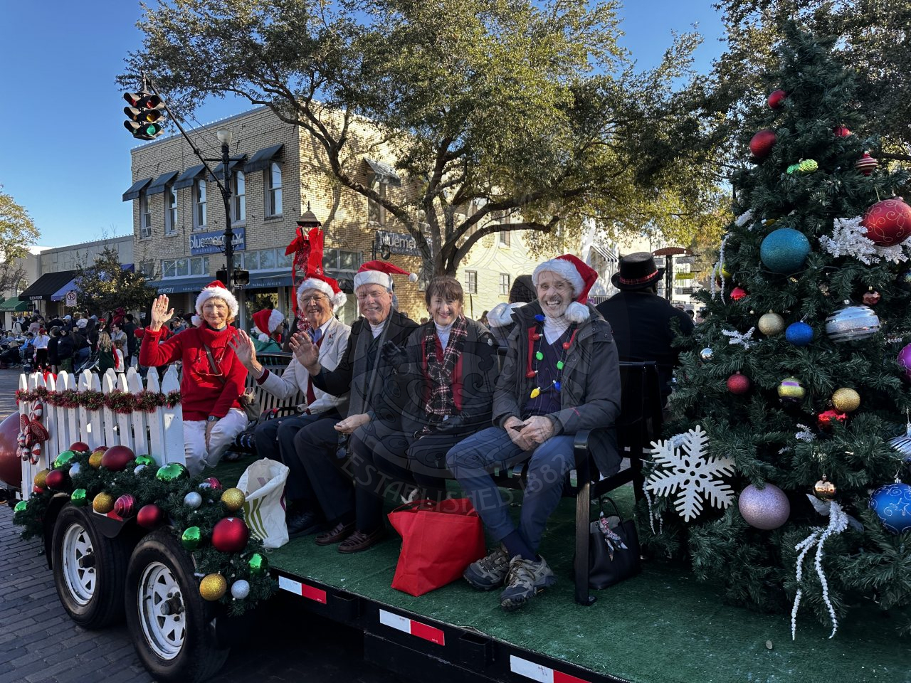 commissioners sitting on a bench waving and smiling.