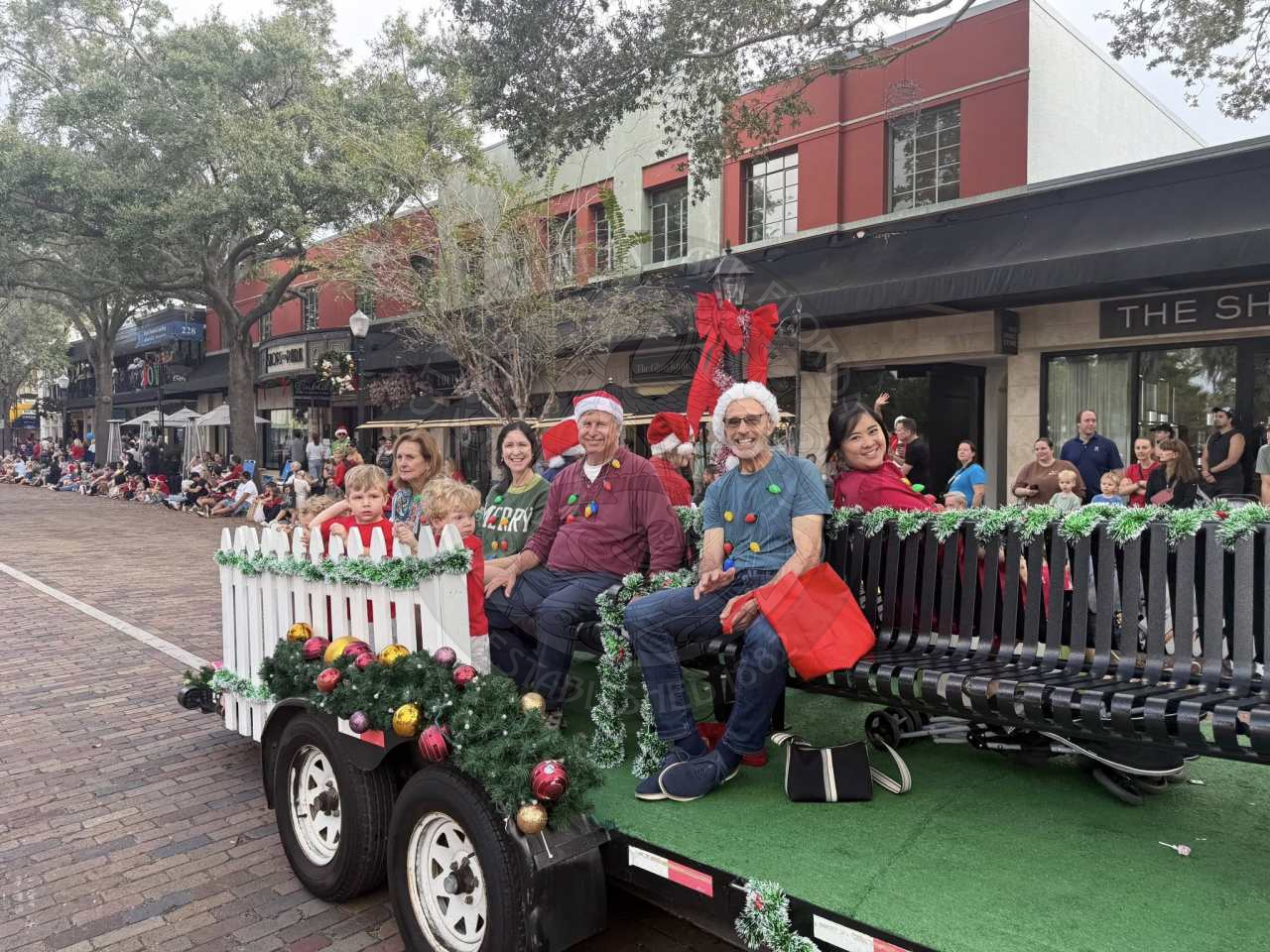 group of people sitting on benches on a trailer riding around on parade float route.