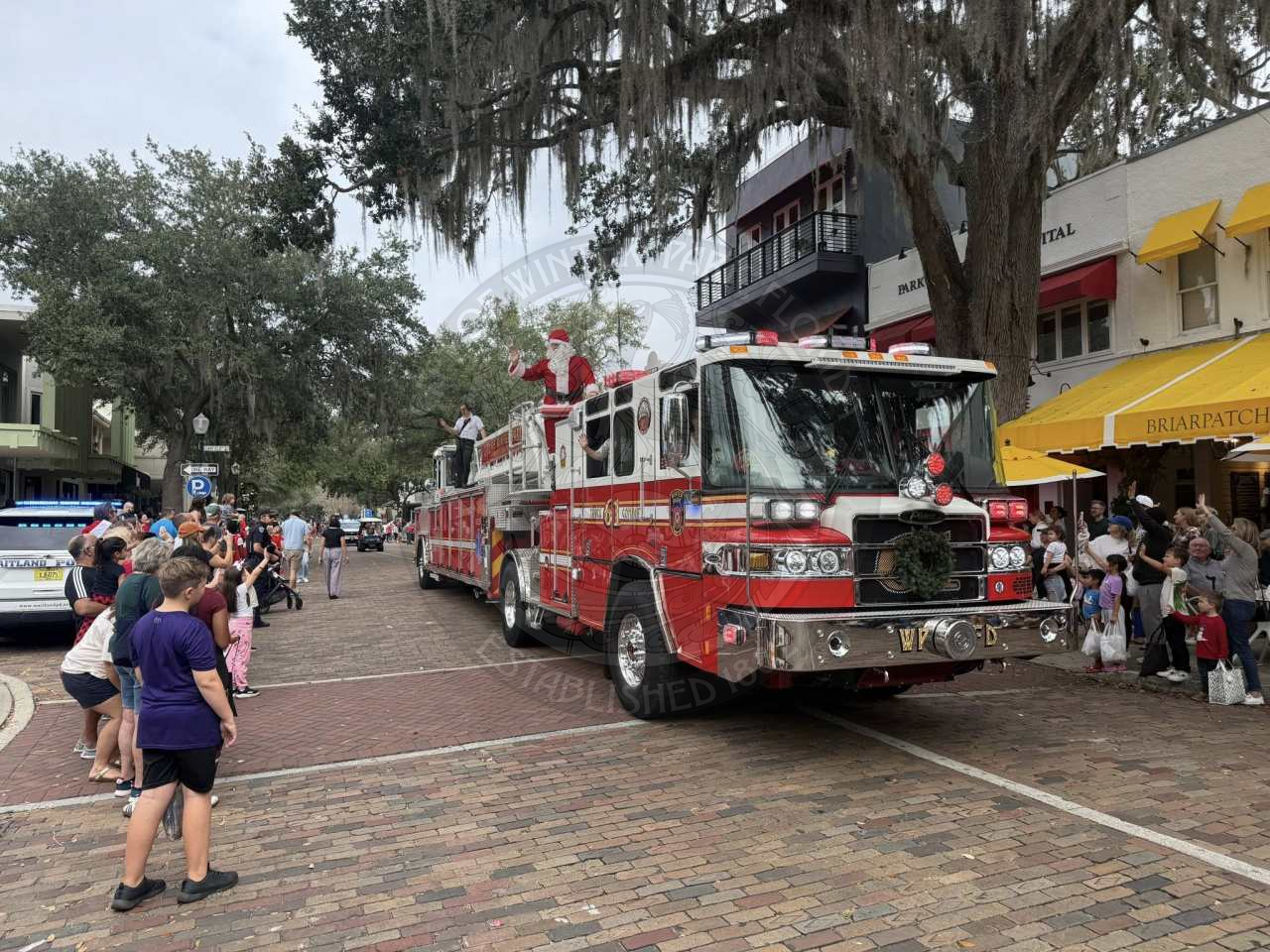 Santa Claus riding in a firetruck along the parade route.
