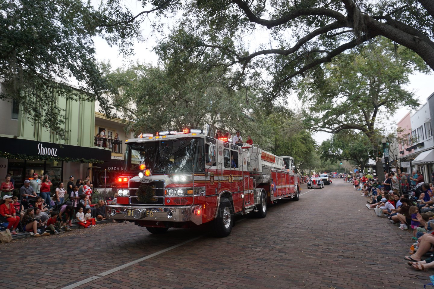 Firetruck riding along the parade route on a brick road.