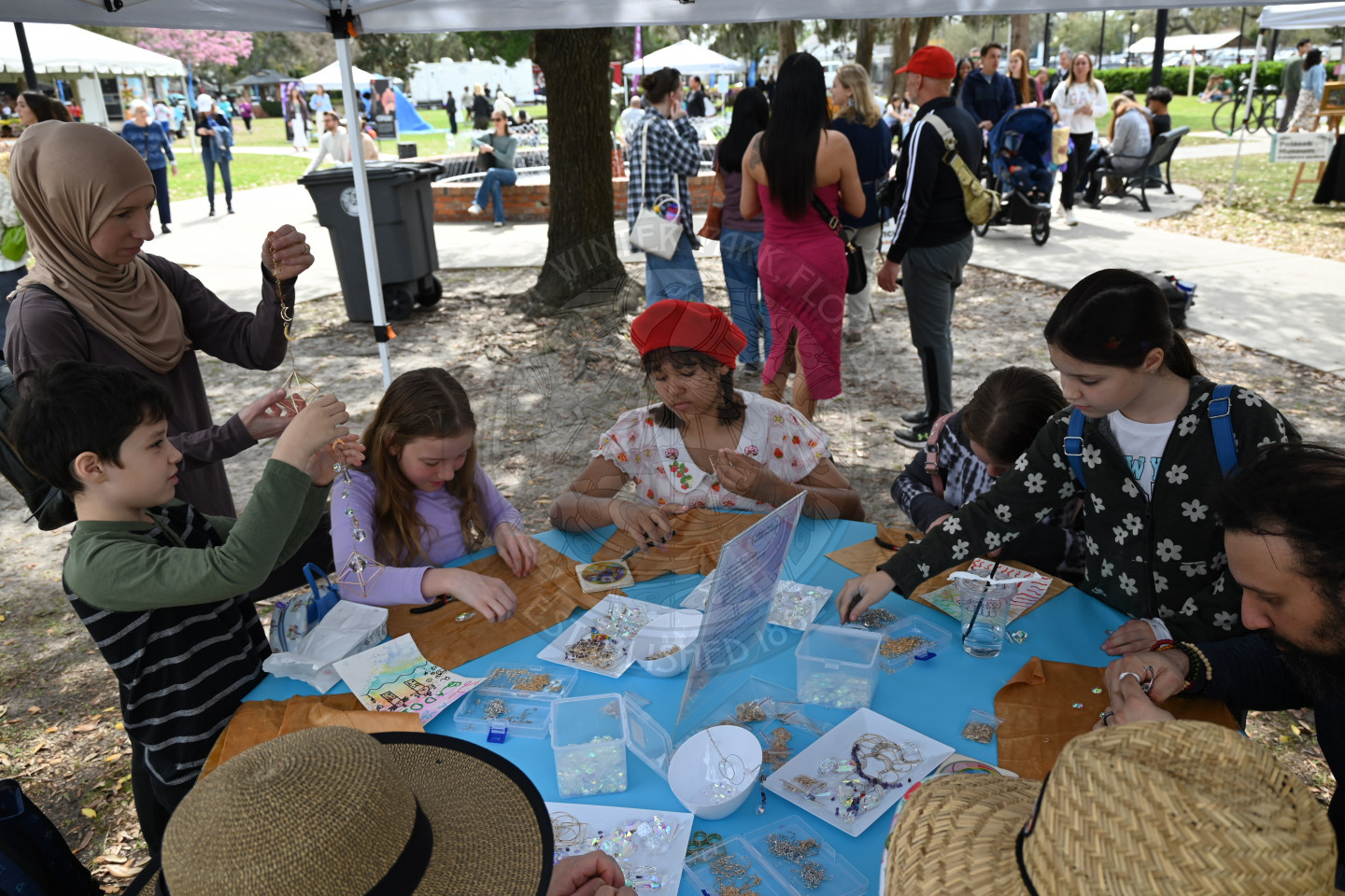 kids sitting down at a table making peices of jewlery.
