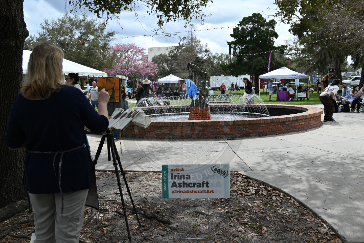 a woman painting Emily Founatin on a small canvas while standing in front of the fountain.