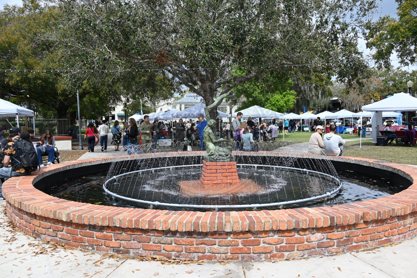 a view of Emily Fountain with tents in the background and people walking around.