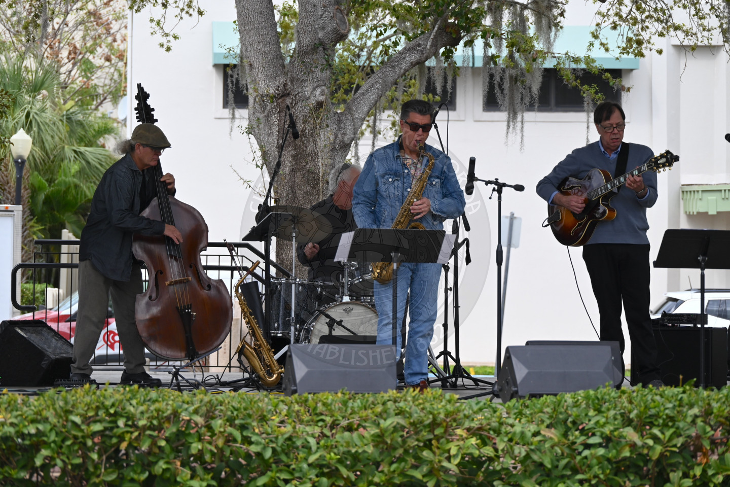 a three person band playing on the stage providing music to attendees.