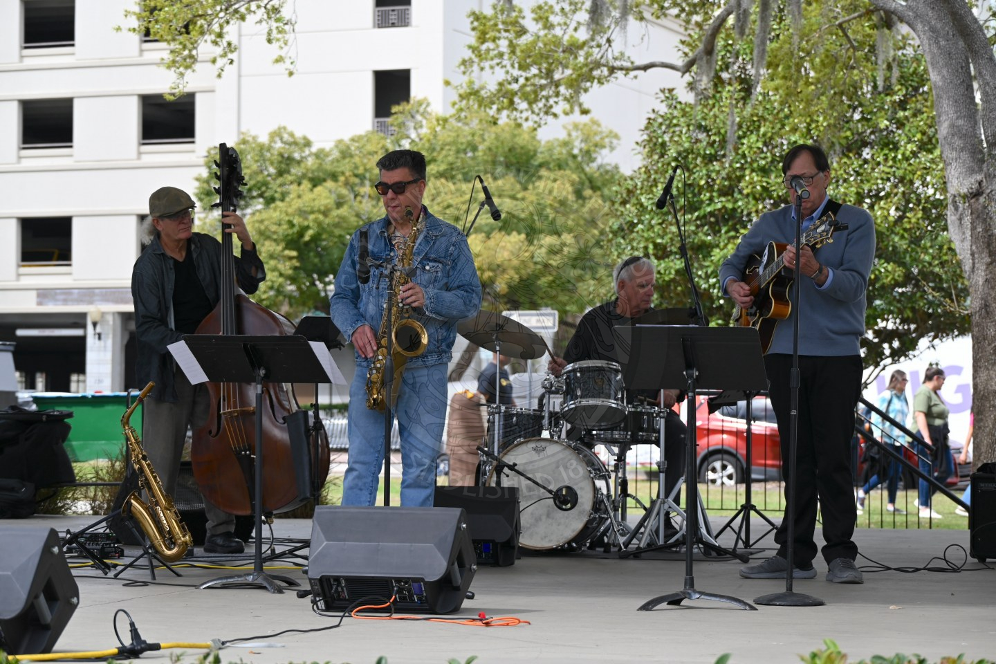 a three person band playing on the stage providing music to attendees.