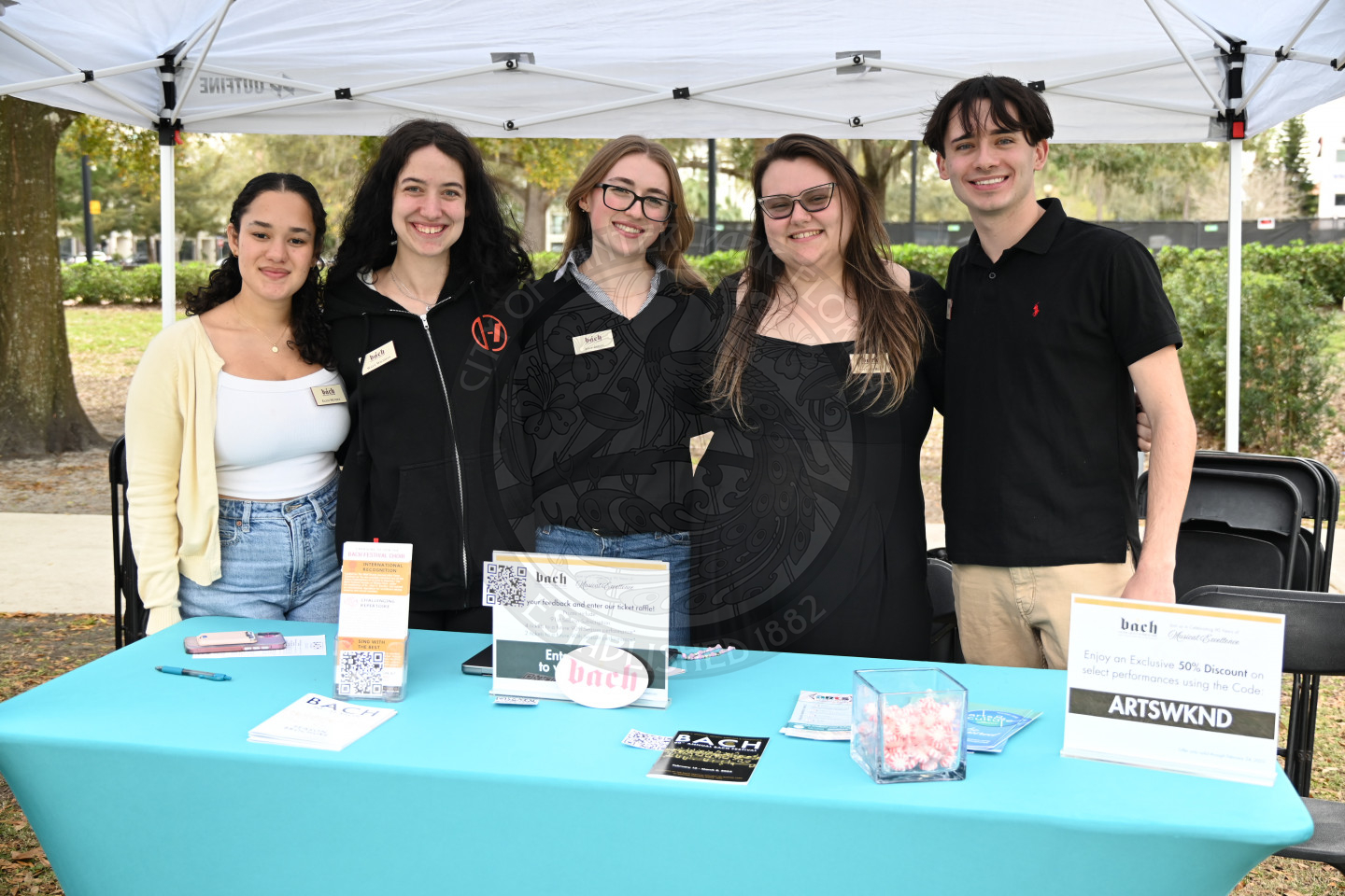 group of young adults standing behind a table smiling and standing next to each other.