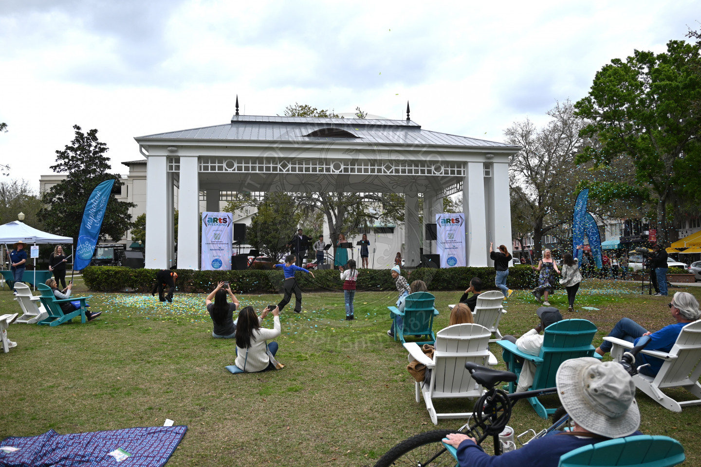 people sitting, standing and dancing in front of the stage as a group of performs on stage.