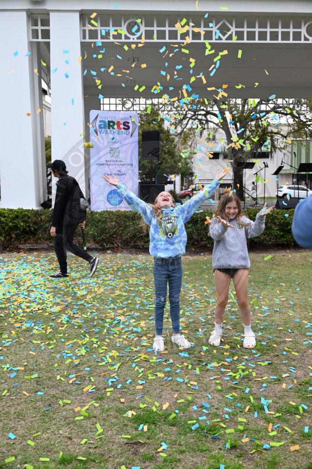 two little girls with their hand in the air throwing around confetti