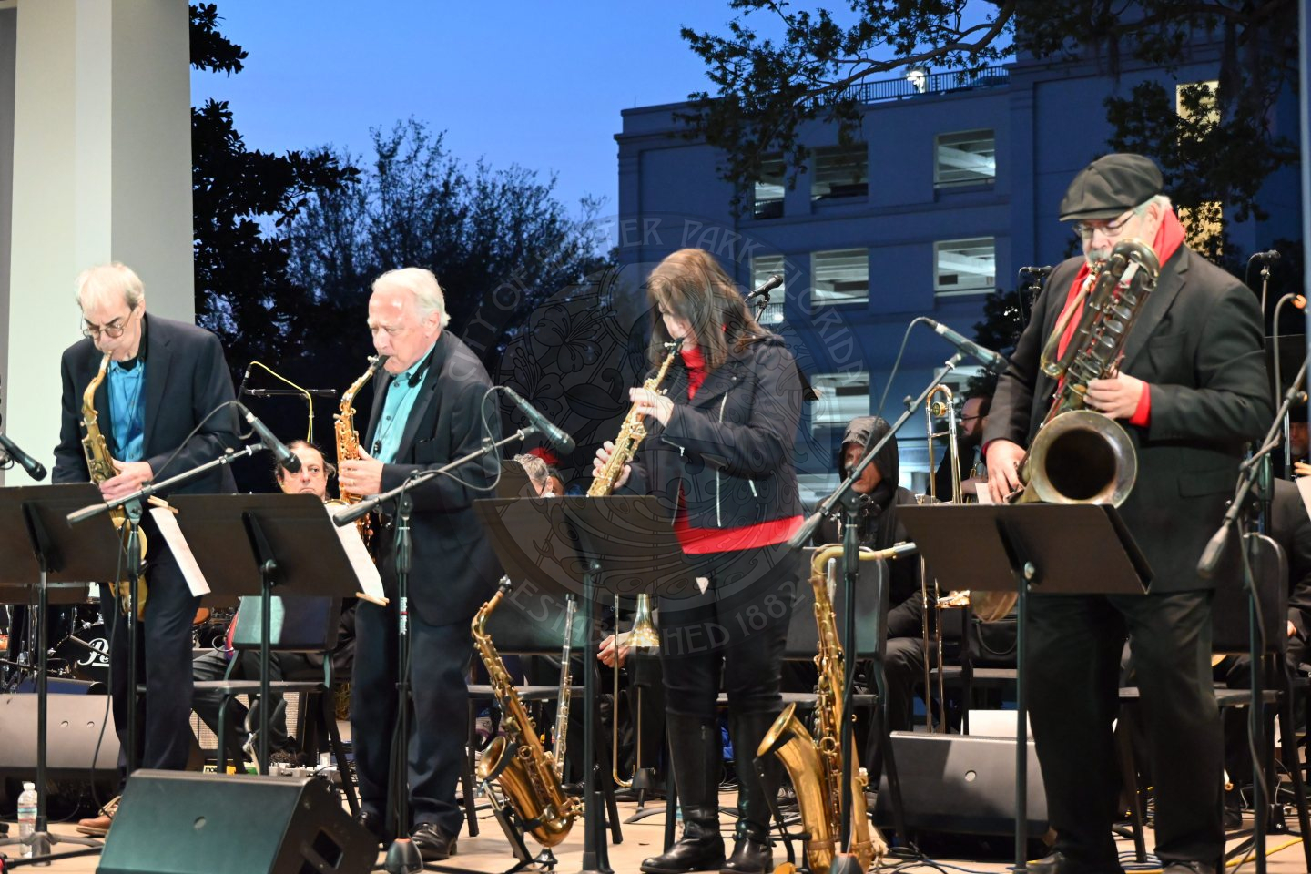 a group of saxophone players playing their instruments and looking at sheet music.