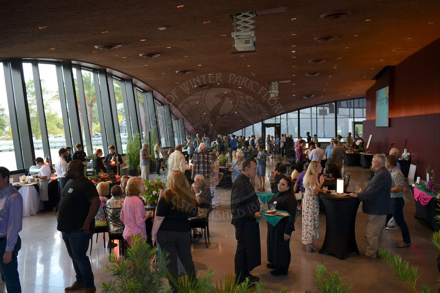 People standing and sitting in a ballroom while drinking and eating food
