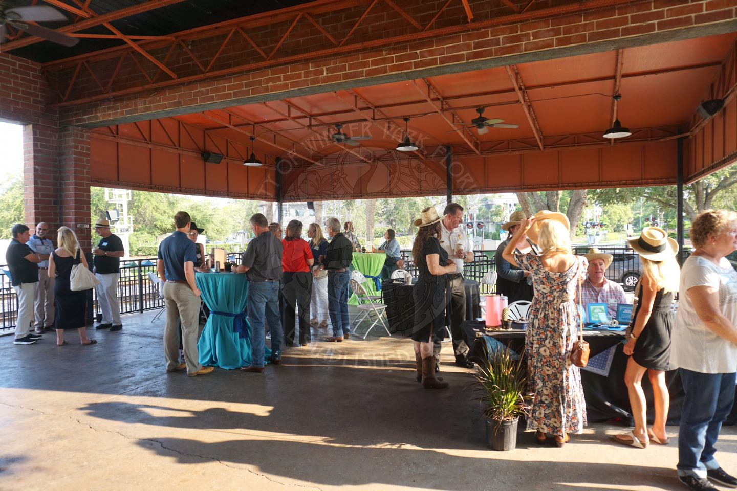 Group of people mingling standing by high top tables while drinking and eating